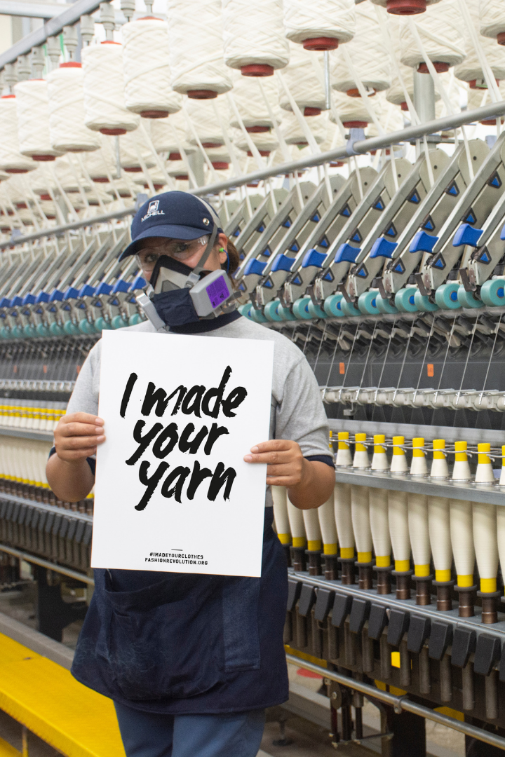 Worker at the Michell spinning mill in Peru holding a sign that reads I made your yarn